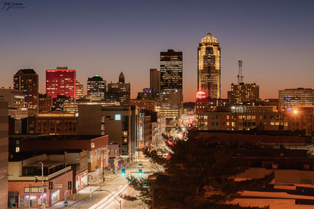 East Village Des Moines skyline bathed in warm sunset hues, showcasing a blend of modern and historic architecture, reflecting the district's trendy and eclectic atmosphere.