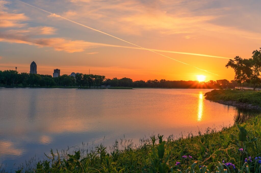 Serene sunset view of Grays Lake Park, with the sky painted in warm hues reflecting on the calm water, creating a picturesque and tranquil scene for visitors to enjoy.