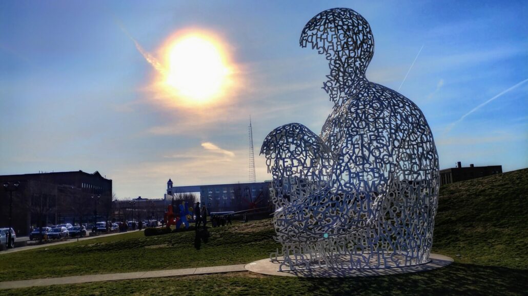 A photograph of Pappajohn Sculpture Park in Des Moines, showcasing contemporary sculptures against the city skyline.