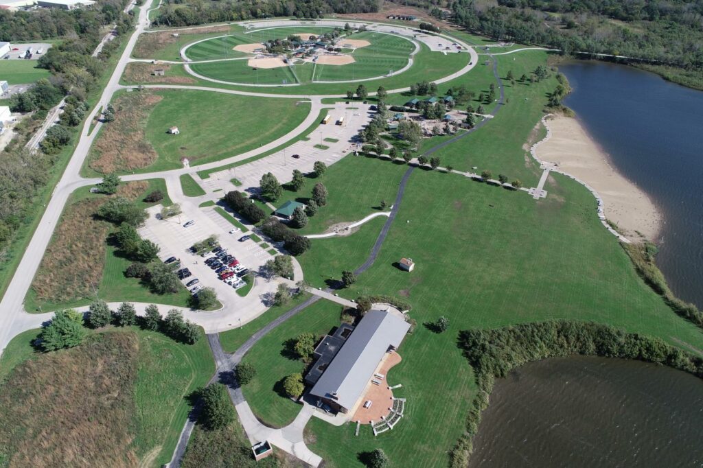 Aerial view of Raccoon River Park, capturing its vast green spaces, winding trails, serene lake, and recreational facilities, showcasing an idyllic retreat for outdoor enthusiasts and nature lovers alike.