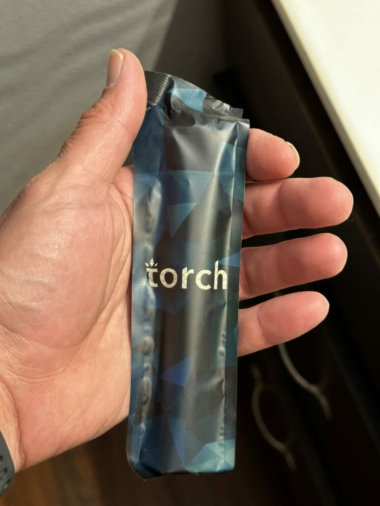 A photo of the Torch Burnout Blend Disposable device in a plastic tamper-evidence bag.