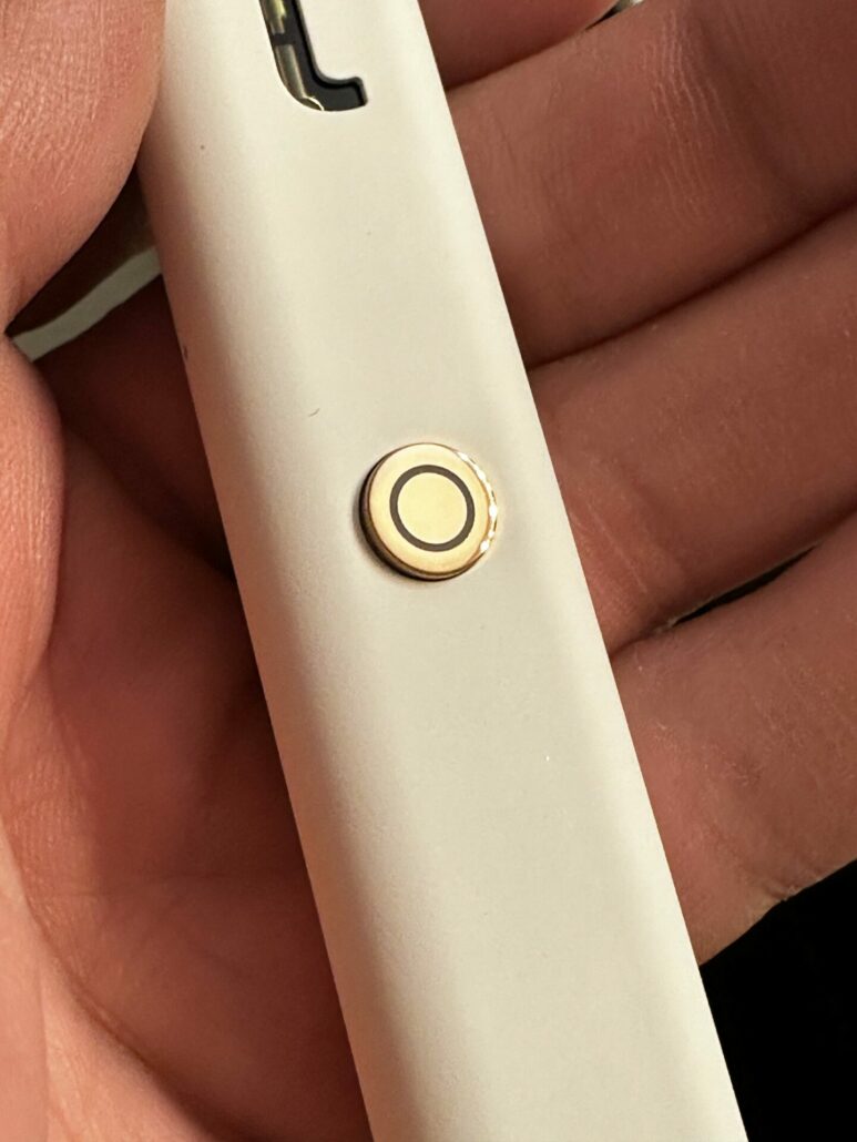 A close-up photo of the power button on the Torch Burnout Blend Disposable device, showing the yellow accent and the five clicks needed to turn the device on and off.