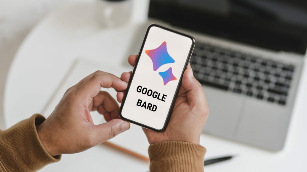 Feature image for the post, "Google Bard: A Comprehensive Guide to Using Google's Answer to ChatGPT" featuring a pair of hands holding a phone displaying the Google Bard Logo.